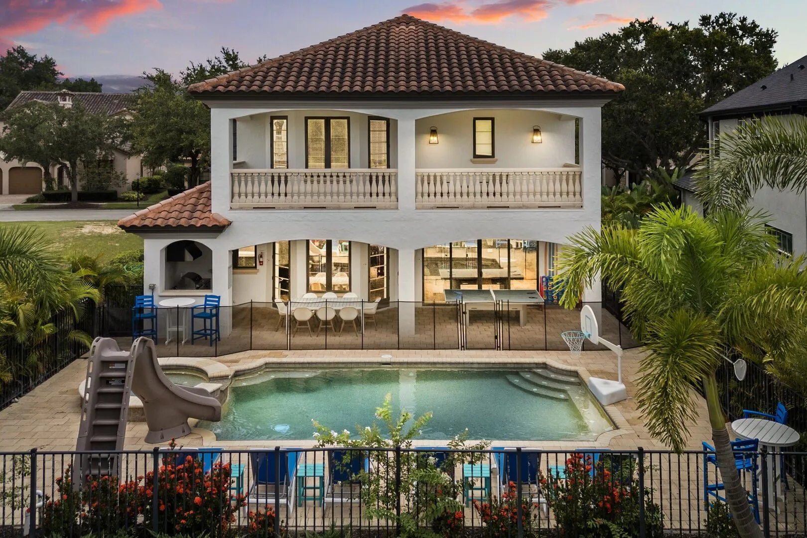 The Sophisticated Estate's private screened pool with a slide and the two-story Mediterranean exterior at twilight