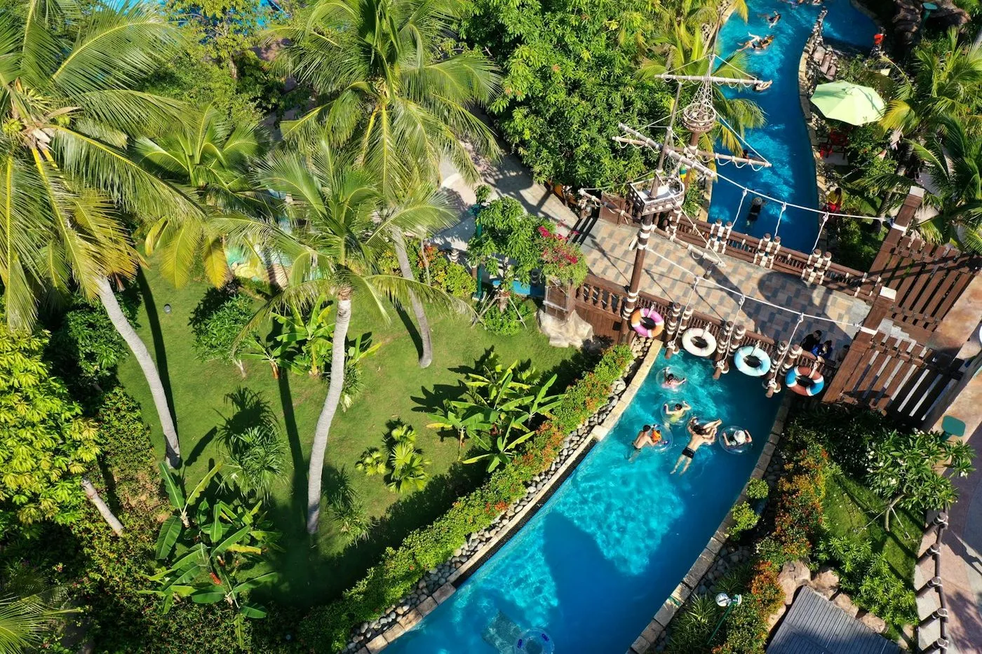 An aerial view of a resort lazy river winding through palm trees
