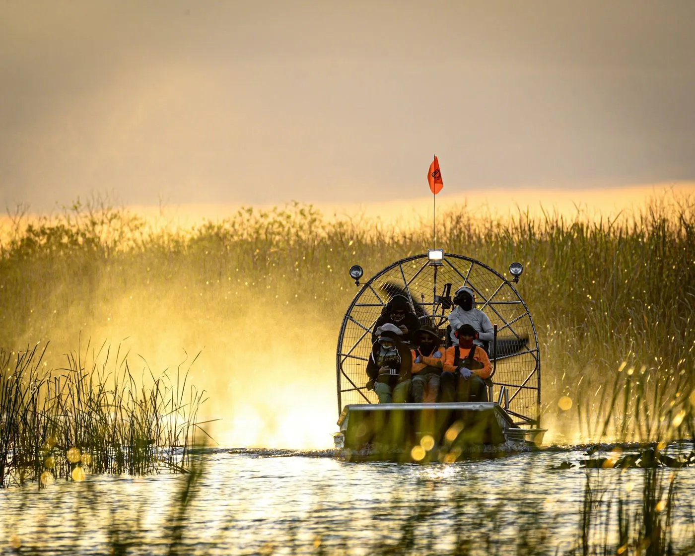 An airboat gliding across a Kissimmee lake at sunset